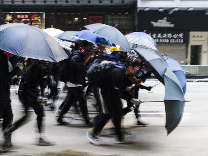Demonstranten schützen sich auf einer Straße mit Regenschirmen.