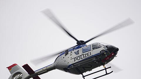 Ein Polizeihubschrauber fliegt bei einem Sucheinsatz über eine Stadt.