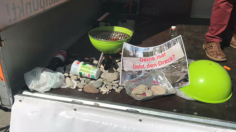 Ein kleiner Grill, leere Flaschen und Plastikmüll sollen die Situation an der Isar verdeutlichen.
