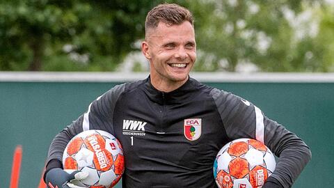 Torwart Rafal Gikiewicz trägt lachend Bälle.