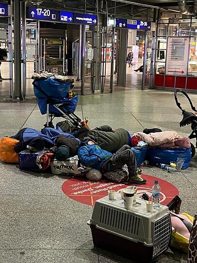 Erschöpfte Kinder aus der Ukraine schlafen in der Bahnhofshalle. Die Erwachsenen haben Tüten und Reisetaschen zusammengestellt, damit sie nicht auf dem blanken Steinboden liegen müssen. Dieses Foto wurde nachts von einem ehrenamtlichen Helfer gemacht.