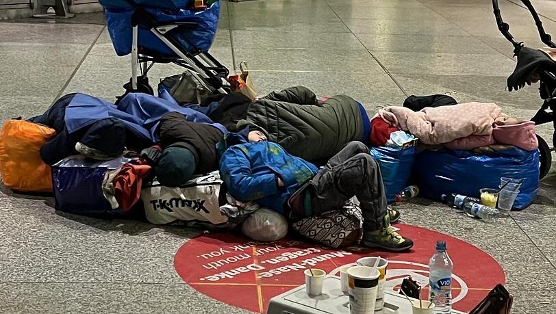 Erschöpfte Kinder aus der Ukraine schlafen in der Bahnhofshalle. Die Erwachsenen haben Tüten und Reisetaschen zusammengestellt, damit sie nicht auf dem blanken Steinboden liegen müssen. Dieses Foto wurde nachts von einem ehrenamtlichen Helfer gemacht. Erschöpfte Kinder aus der Ukraine schlafen in der Bahnhofshalle. Die Erwachsenen haben Tüten und Reisetaschen zusammengestellt, damit sie nicht auf dem blanken Steinboden liegen müssen. Dieses Foto wurde nachts von einem ehrenamtlichen Helfer gemacht.