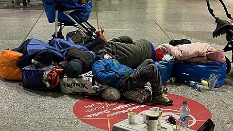 Erschöpfte Kinder aus der Ukraine schlafen in der Bahnhofshalle. Die Erwachsenen haben Tüten und Reisetaschen zusammengestellt, damit sie nicht auf dem blanken Steinboden liegen müssen. Dieses Foto wurde nachts von einem ehrenamtlichen Helfer gemacht.