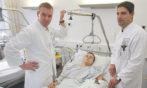 Prof. Raymund Horch (l.) und Adrian Dragu am Bett von Waldemar R. (26). Der Patient &ndash; er hat am Dienstag Geburtstag &ndash; wird seine Hand wieder benutzen können.