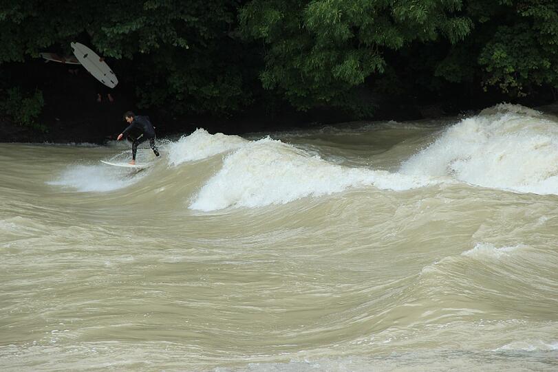 Hochwasser für die einen, perfekte Wellen für die anderen. Waghalsig tummeln sich Sportler in der Isar.