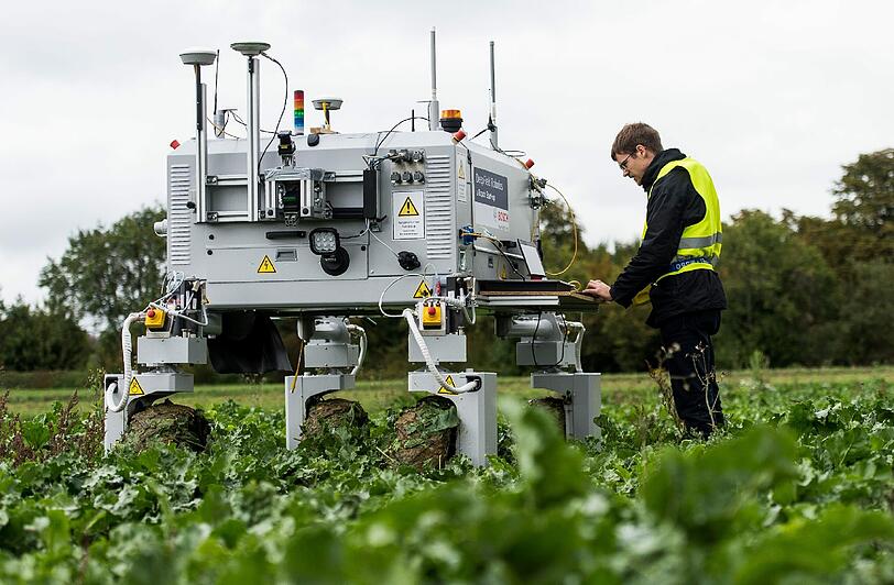 Ein Bosch Mitarbeiter steht auf einem Feld neben dem Agrarroboter Bonirob. Die Landwirtschaft steht vor einem tiefgreifenden Wandel. Foto: Daniel Maurer