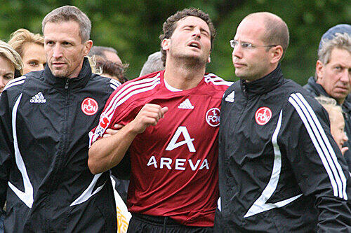Es sah viel schlimmer aus: Ioannis Masmanidis wird von Teamarzt Matthias Brem (r.) und Physio Ralf Scheuchl (l.) vom Platz geführt.