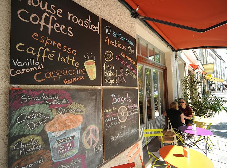 Auf der bunten Sonnenterrasse vor dem Café lässt sich das ebenso bunte Treiben auf der Lindwurmstraße beobachten.