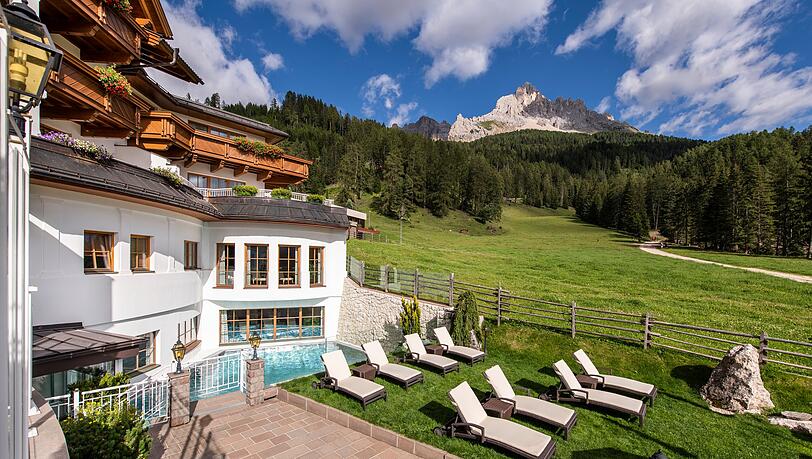 Das Genießerhotel Sonnalp mit Wellnessbereich vor dem imposanten Gipfel des Latemar. Das Vier-Sterne-Superior-Hotel liegt auf 1550 Metern im Südtiroler Obereggen – nicht weit von Bozen.