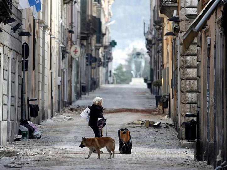 Wie leergefegt: Eine Italienerin läuft nach dem Erdbeben durch eine menschenleere Straße in L'Aquila.