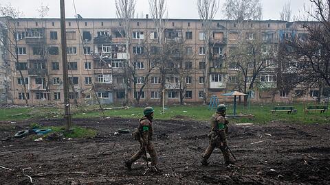 Ukrainische Soldaten gehen in Bachmut an stark beschädigten Gebäuden vorbei.