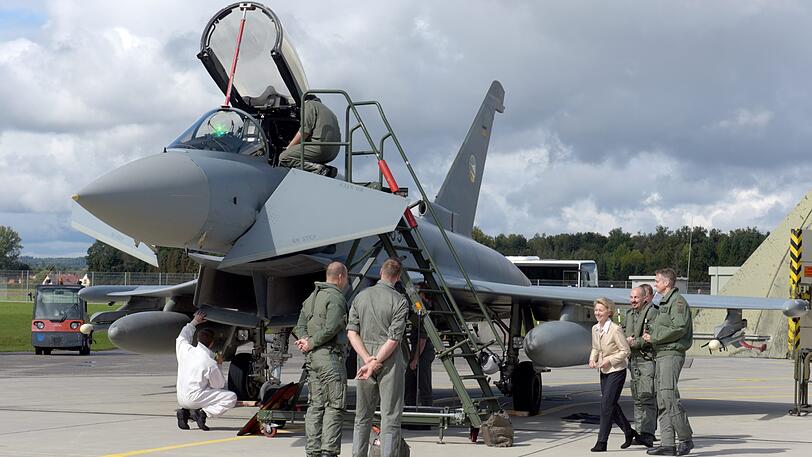 Verteidigungsministerin Ursula von der Leyen (CDU) steht beim Taktischen Luftwaffengeschwader 74 zusammen mit dem Kommodore Holger Neumann (r) und dem fliegenden Kommandeur Swen Jacob (2.v.r) vor einem Kampfflugzeug vom Typ Eurofighter.