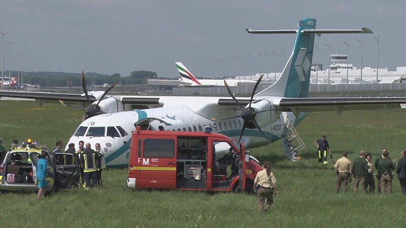Mitarbeiter des Flughafens in München betrachten die Maschine der italienischen Fluggesellschaft, die am Donnerstag auf dem Münchner Flughafen notlanden musste. Das Flugzeug mit 62 Menschen an Bord hatte kurz nach dem Start in Richtung Venedig umdrehen müssen, weil sich Rauch in der Kabine entwickelt hatte. Bei der Landung wurden fünf Personen leicht verletzt, die Maschine kam neben der Landebahn zum Stehen.