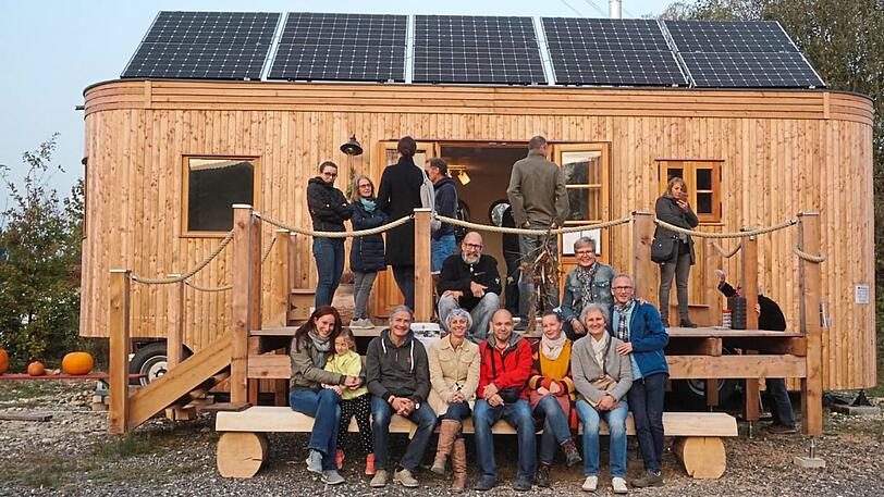 Ein "Wohnwagon" &ndash; ein Tiny House aus Österreich. Die zukünftige Dorfgemeinschaft &ndash; auf der Bank, Thorsten Thane mit schwarzem Pulli &ndash; hat es besichtigt.