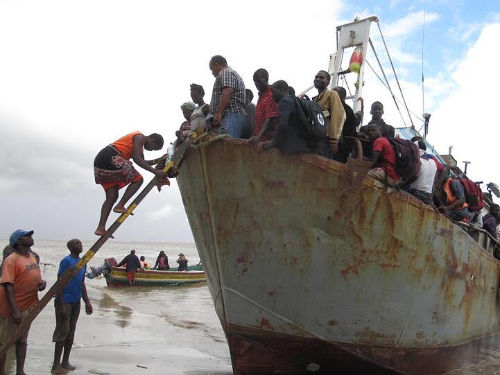 Ein Boot mit etwa 100 Menschen, die aus der überfluteten Region Buzi gerettet wurden, legt an einem Strand an.