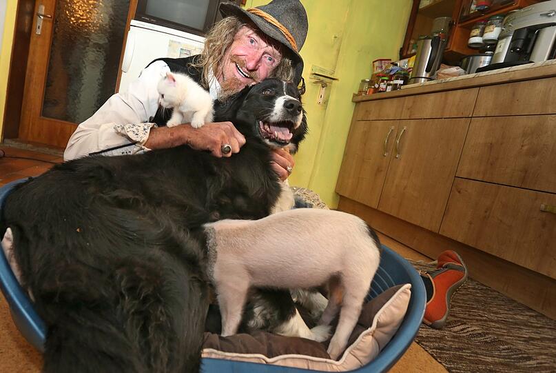 Dieter Schetz, Zirkusdirektor eines Kleintierzirkus, hält in seinem Haus Hündin Molly die gerade das knapp sechs Wochen alte Ferkel Rosa säugt.