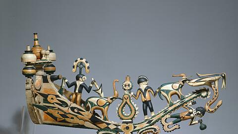 Der Schiffsschnabel kam während der Kolonialzeit 1884 als Kriegsbeute von Kamerun nach Deutschland. Im Herkunftsland erheben verschiedene Parteien Anspruch auf das Herrschaftszeichen, vor allem Prinz Kum&rsquo;a Ndumbe III., der sogar von einer Königsinsignie spricht.