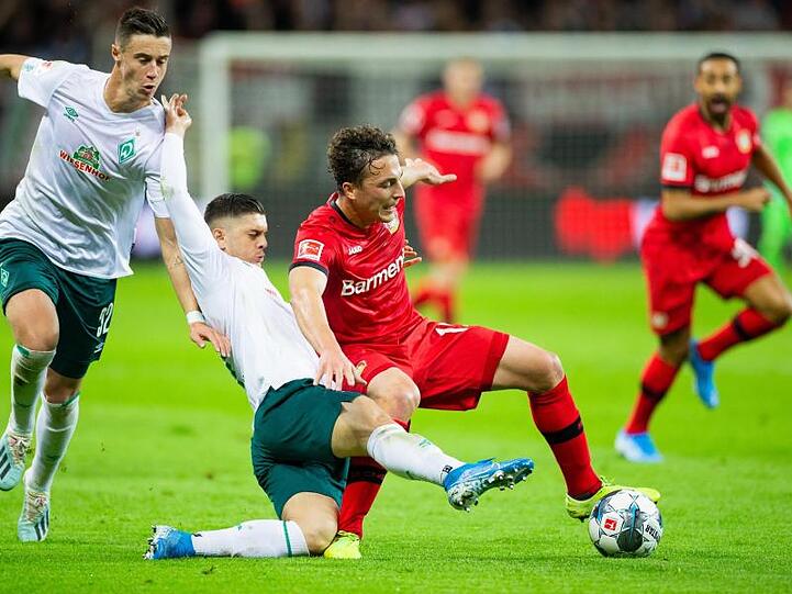 Leverkusens Julian Baumgartlinger (r) wird von Bremens Milot Rashica zu Fall gebracht, links läuft Bremens Marco Friedl.