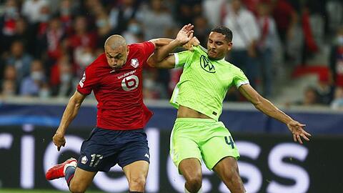 Maxence Lacroix vom VfL Wolfsburg (r) kann sich im Kampf um den Ball nicht gegen Burak Yilmaz vom OSC Lille durchsetzen.