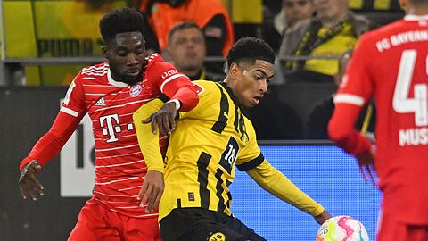 Dortmunds Jude Bellingham (r) und Münchens Alphonso Davies kämpfen um den Ball.