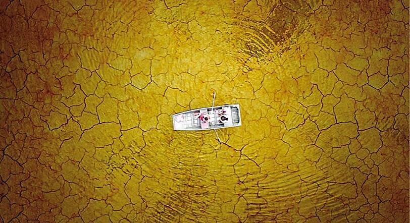 Der Boden glänzt wie Gold und hat Risse wie nach einer Dürre: Das Bild zeigt ein Boot auf dem Burke Lake in den USA. Der Fotograf: Milo Allerton.