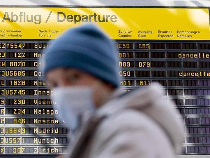 Ein Mann mit Mundschutz steht am Flughafen Berlin-Tegel vor der Anzeigetafel der Abflüge.