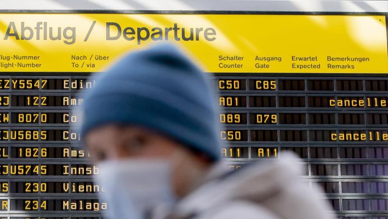 Ein Mann mit Mundschutz steht am Flughafen Berlin-Tegel vor der Anzeigetafel der Abflüge.