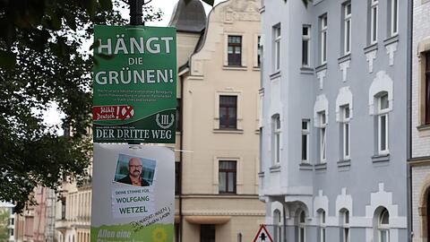 Ein hetzerisches Wahlplakat der Splitterpartei "III Weg" hängt über einem Plakat der Grünen.