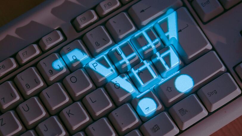 Das Symbol eines Einkaufskorbs leuchtet auf einer Computertastatur.