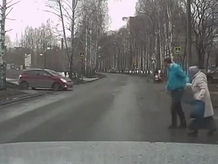 Hier hilft ein junger Mann einer älteren Dame über die Straße