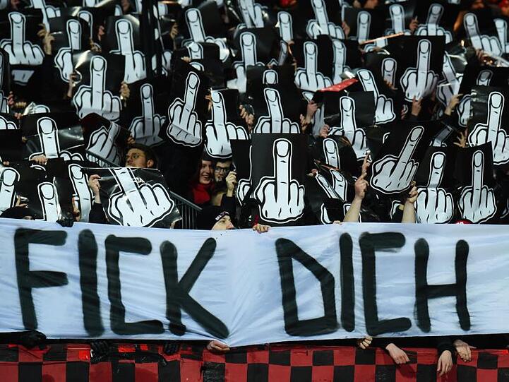 Nürnberg-Fans mit Schildern in Mittelfinger-Form und einem Banner mit dem Slogan "Fick dich DFB". Foto: Nicolas Armer/dpa