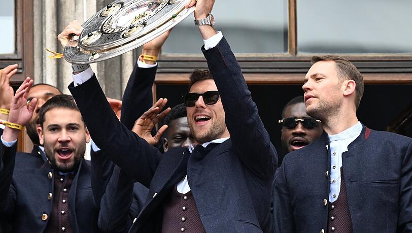 Die von ihrem Erfolg leicht gelangweilten Millionäre des FC Bayern auf dem Rathausbalkon. Die von ihrem Erfolg leicht gelangweilten Millionäre des FC Bayern auf dem Rathausbalkon.