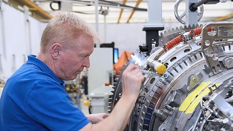 Ein Mitarbeiter arbeitet in einem Werk der MTU Aero Engines AG an einer Flugzeug-Turbine. Foto: -/MTU Aero Engines AG/dpa/Archivbild