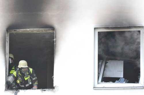 Ein Feuerwehrmann schaut aus einem der verkohletn Fenster.