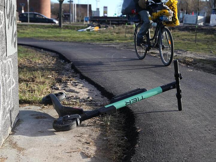 Ein Radfahrer weicht auf einem Radweg einem umgekippten E-Tretroller aus.