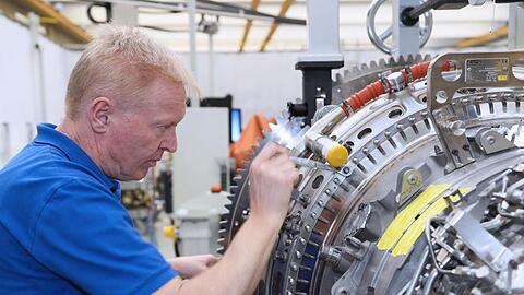 Ein Mitarbeiter arbeitet in einem Werk der MTU Aero Engines AG an einer Flugzeug-Turbine.