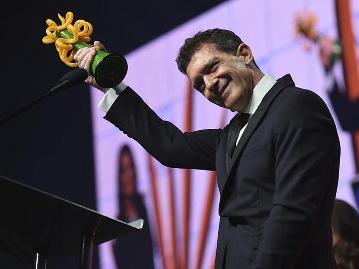 Antonio Banderas winkt mit seinem Award ins Publikum.