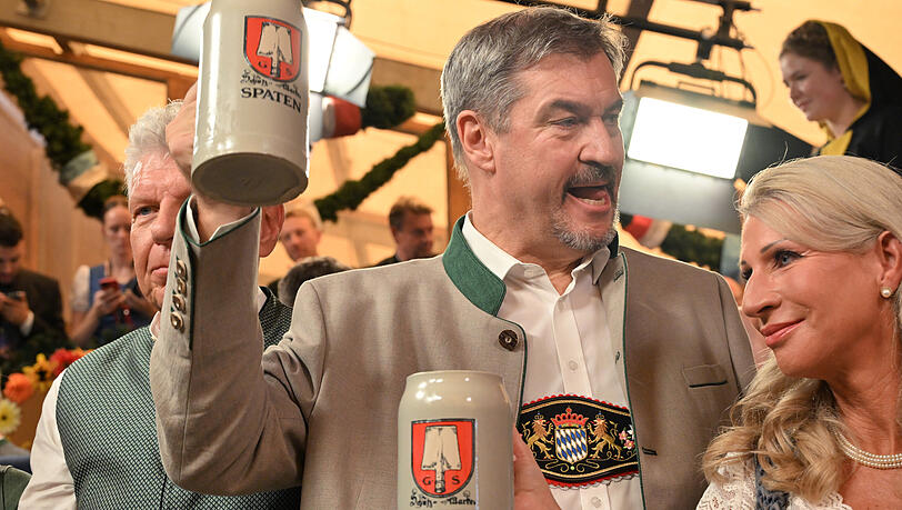 Markus Söder (CSU, M), Ministerpräsident von Bayern, und seine Frau Karin Baumüller-Söder trinken neben Dieter Reiter (SPD, l), Oberbürgermeister von München, nach dem Anstich des ersten Oktoberfestfasses im Schottenhammel-Festzelt Bier. Die Wiesn findet vom 21. September bis 6. Oktober 2024 statt.