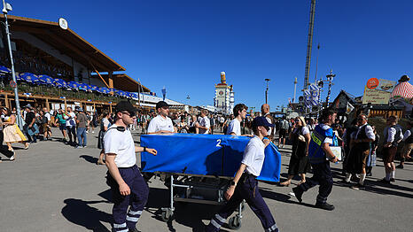 Mitarbeiter der Oktoberfest-Ambulanz gehen am ersten Tag des Oktoberfestes über das Festgelände.