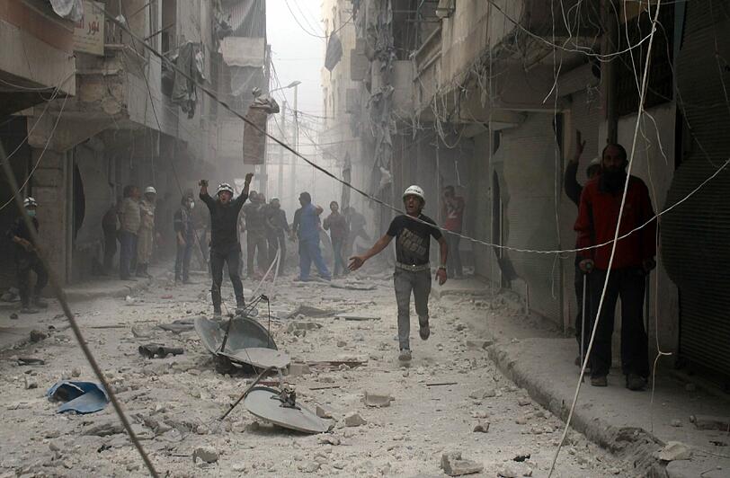 Syrische Rettungskräfte winken durch die Staubwolken direkt nach einem Luftangriff durch Regirungsstreitkräfte in Aleppo. Hier tobt immernoch der Bürgerkrieg, inzwischen weitgehend unbeachtet von den Medien.