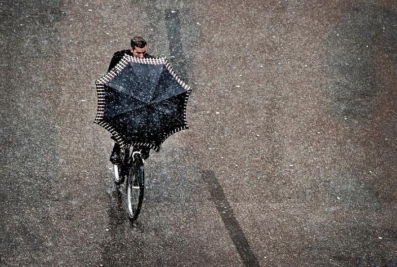 In der Münchner Innenstadt bleibt es erstmal beim Schneeregen. Für Radler eine besondere Herausforderung, auch und gerade mit Schirm.