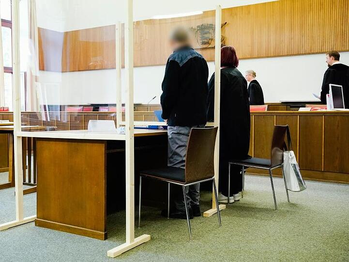 Der Angeklagte steht neben seiner Verteidigerin im Verhandlungssaal des Landgerichts.