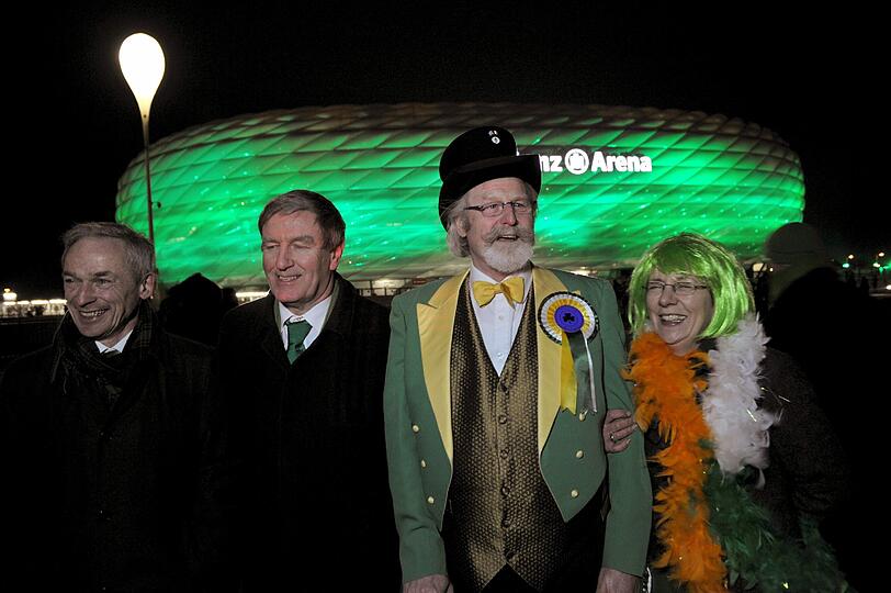 Der irische Wirtschaftsminister Richard Bruton (v-l), der irische Botschafter Daniel Mulhall und zwei unbekannte Personen vom irischen Freundschaftsverein stehen vor der Allianz Arena, die am irischen Nationalfeiertag St. Patrick`s Day am 17.03.2013 in München grün erstrahlt