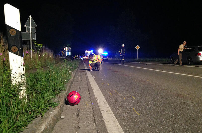 Ein Fußball liegt auf der B12 bei Hergatz (Bayern) im Rinnstein, während die Polizei den Unfall aufnimmt.