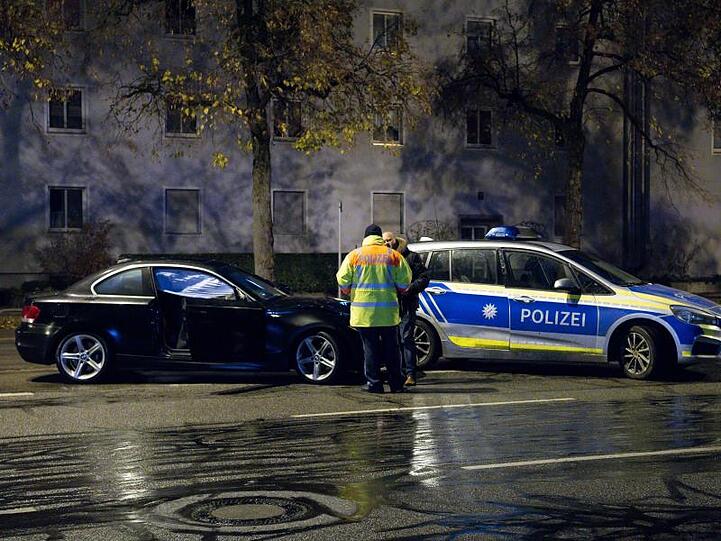 Polizisten stehen nach einem Unfall auf der Fürstenrieder Straße neben einem beschädigten Auto. F. Foto: Sven Hoppe/dpa