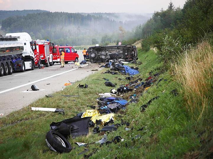 Trümmerteile liegen an der Unfallstelle neben der Autobahn 9, im Hintergrund liegt der umgestürzte Transporter.