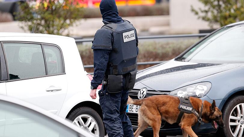 Ein französischer Polizei-Hundeführer patrouilliert einen Parkplatz am Flughafen.