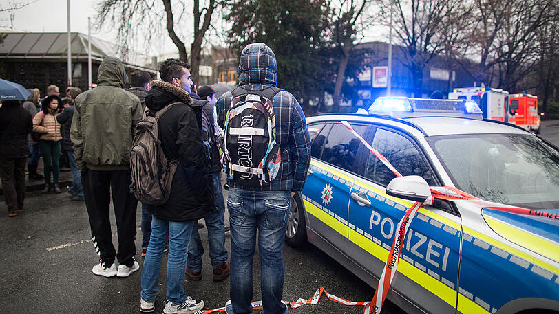 Schüler stehen in Menden (Nordrhein-Westfalen) vor einem Berufkolleg vor einem Polizeiauto. Ein Amok-Fehlalarm hat in einer Schule einen Großeinsatz der Polizei ausgelöst.