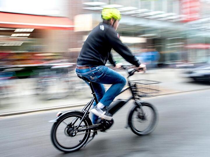 Ein Radfahrer fährt mit einem E-Bike auf einer Straße. Foto: Hauke-Christian Dittrich/dpa/Symbolbild