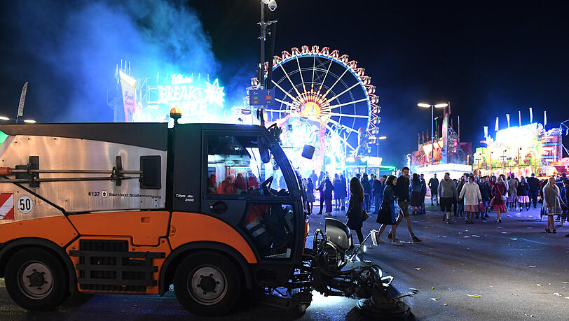 Müll auf dem Oktoberfest: Ein Kehrfahrzeug der Stadtreinigung fährt bei Dunkelheit am Riesenrad vorbei. Müll auf dem Oktoberfest: Ein Kehrfahrzeug der Stadtreinigung fährt bei Dunkelheit am Riesenrad vorbei.